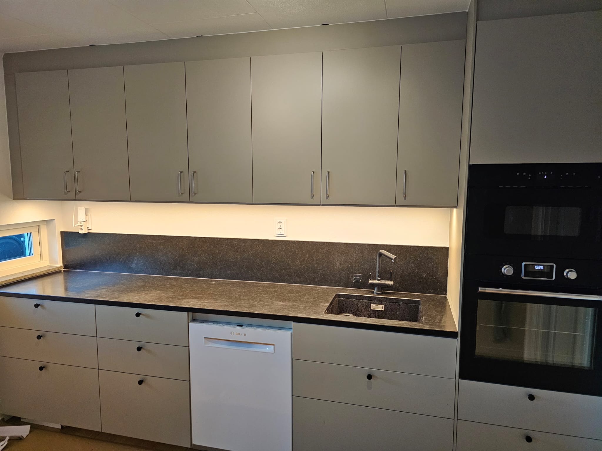 Olive green contemporary kitchen with dark worktops in Malmö