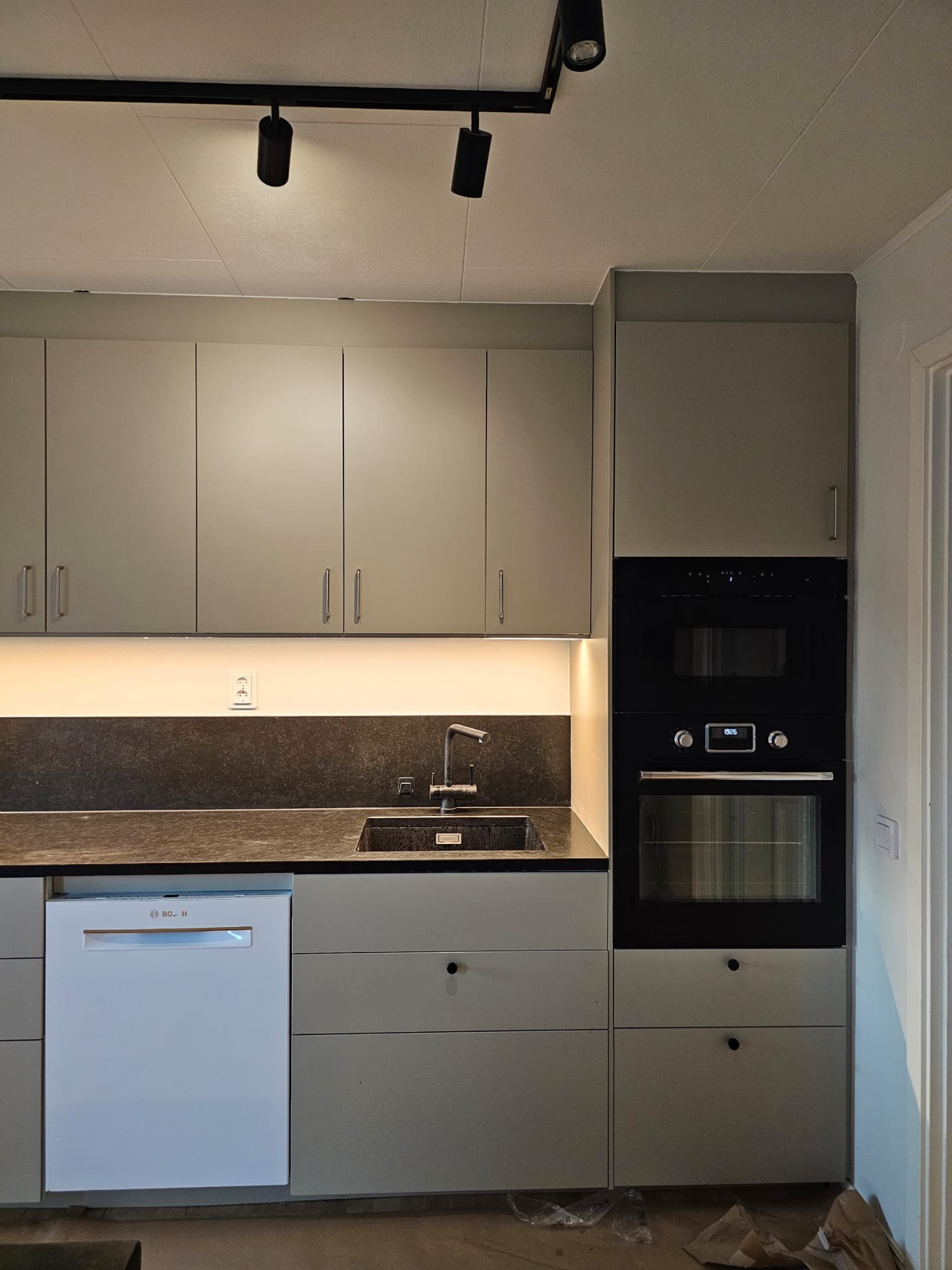 Olive green kitchen cabinetry with integrated black oven in Malmö