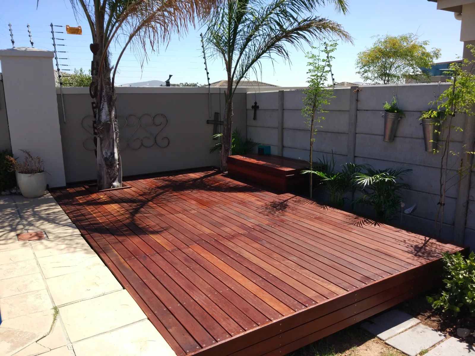 Balau hardwood garden decking built around an existing palm tree with integrated timber seating
